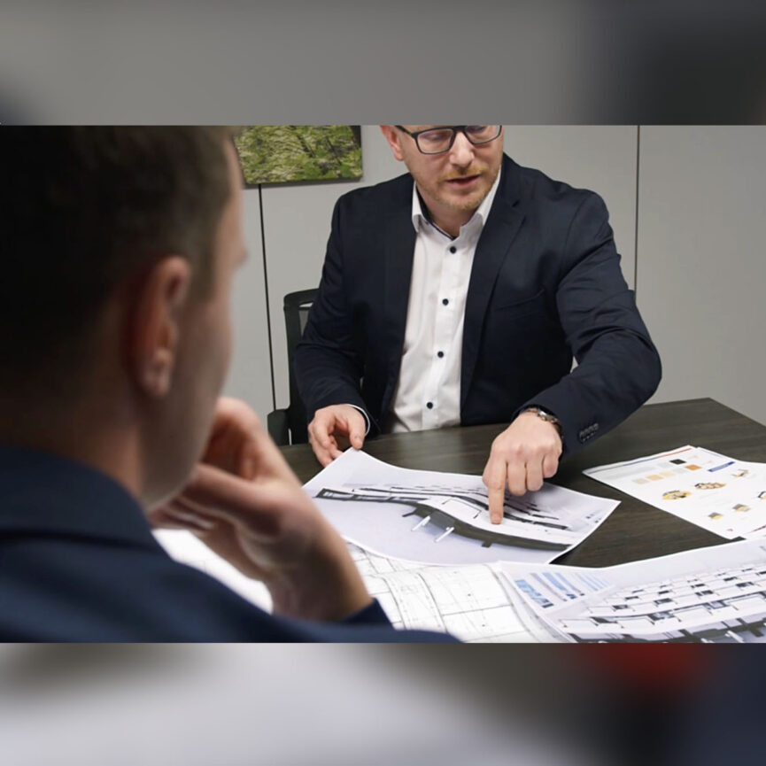 Szenen aus dem Imagefilm Salfer GmbH - Ein Mann sitzt an einem Tisch und zeigt auf einen 3D Plan.